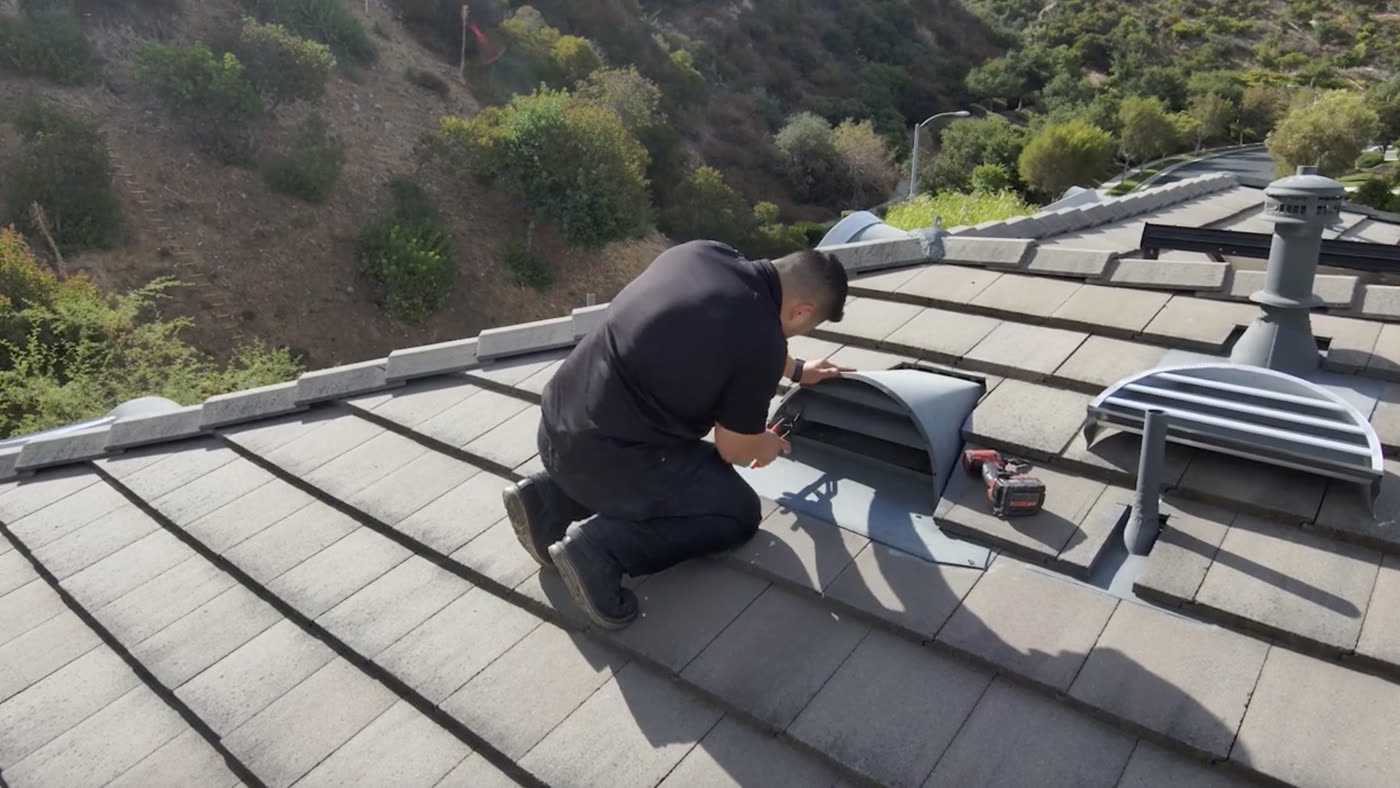 An Allied crew member fitting an ember-resistant dormer vent on a tile roof