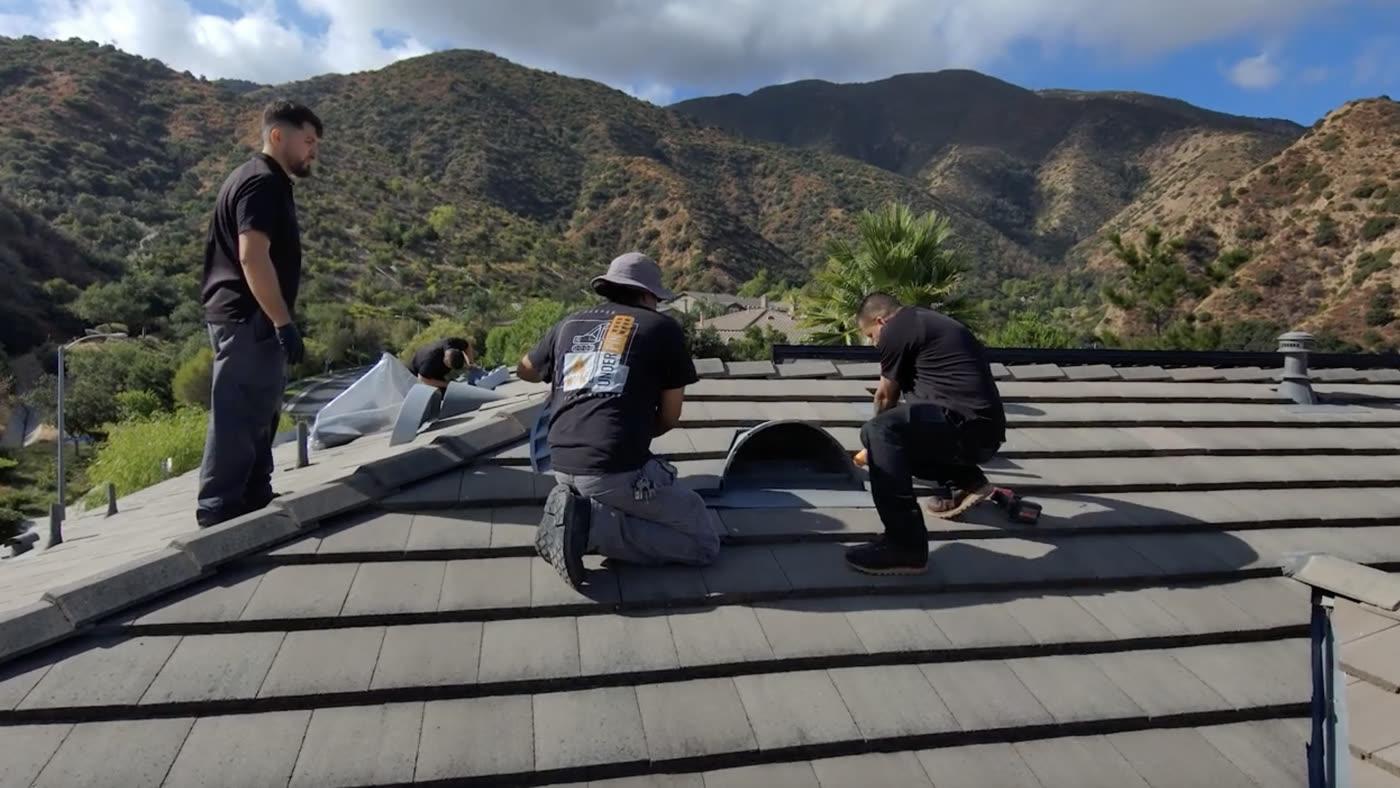 An Allied crew installing ember-resistant venting on an estate roof above a canyon
