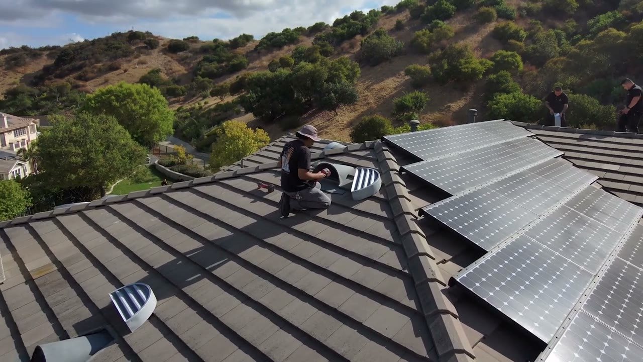 An Allied technician installing an ember-resistant roof vent beside solar panels